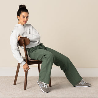 Women’s New Balance 574 sneakers worn by seated model, grey uppers with white laces