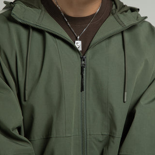 Men's olive windbreaker jacket close-up: hood drawcords and front zipper
