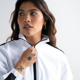 Woman wearing a white jacket with black accents on a plain background
