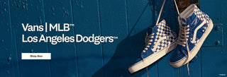 Vans x MLB Los Angeles Dodgers blue-and-white checkerboard high-top sneakers hanging against a blue wall. Shop now.