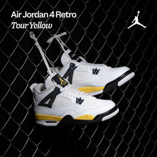 Air Jordan 4 Retro Tour Yellow sneakers against a chain-link fence.