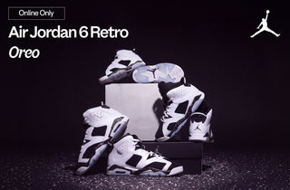 Air Jordan 6 Retro 'Oreo' sneakers in white and black, multiple pairs stacked on shoe boxes against a dark background with speckled detailing. Online Only