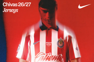 Nike Chivas 26/27 home jersey in red and white vertical stripes with dark collar, Amazon Prime and Caliente sponsor logos, worn by a male model against a red background.